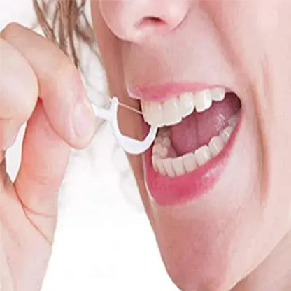 Person using a dental floss pick to clean teeth, close-up on mouth and white teeth